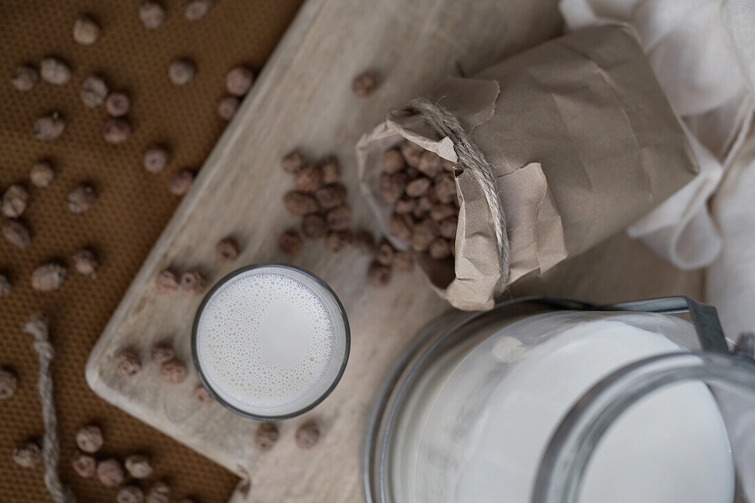 Top view of home made organic horchata drink served in transparent glasses on wooden table near almonds in a rustic kitchen