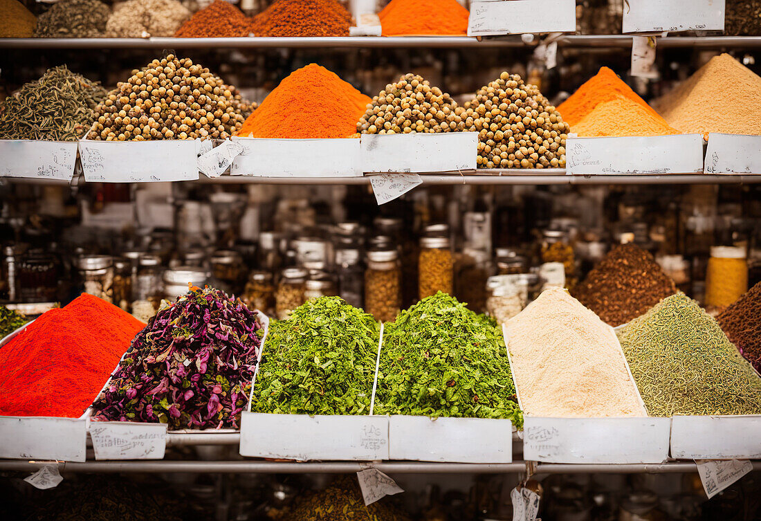 Rows of assorted colored spices and vegetables with seeds in bottles placed on stall in local market