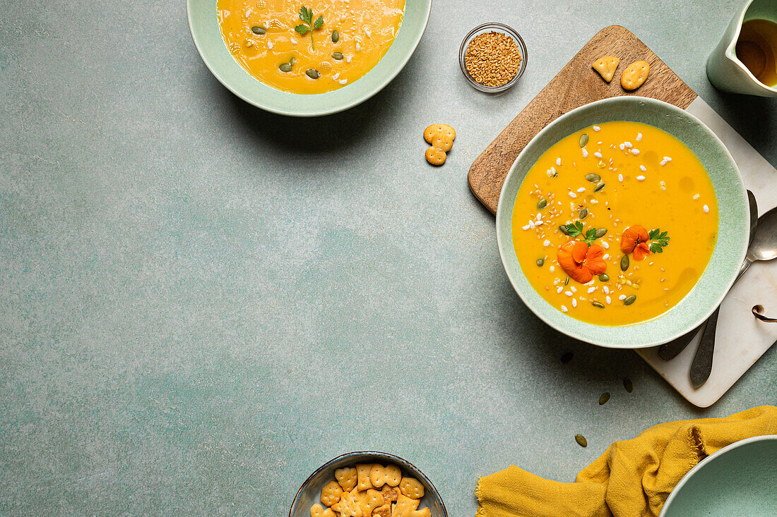 Draufsicht auf eine appetitliche vegetarische Kürbiscremesuppe mit Kräutern und Sesam, serviert in Schalen auf einem Tisch