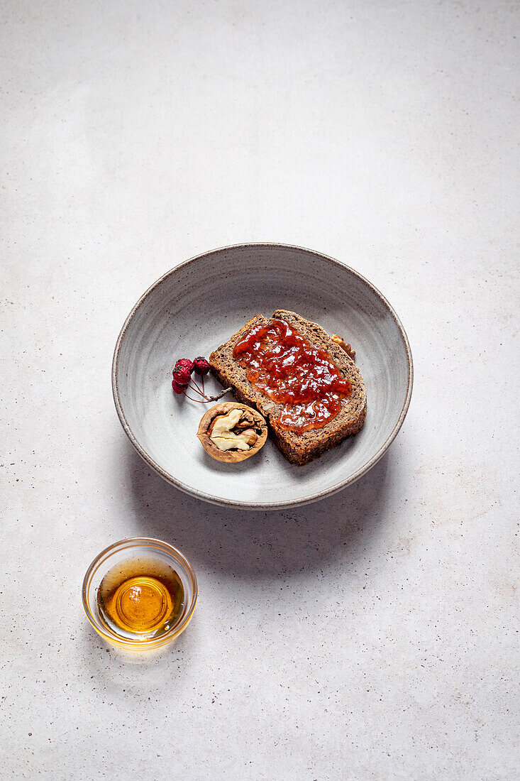 Top view of rye bread with jam near half of walnut composed with honey