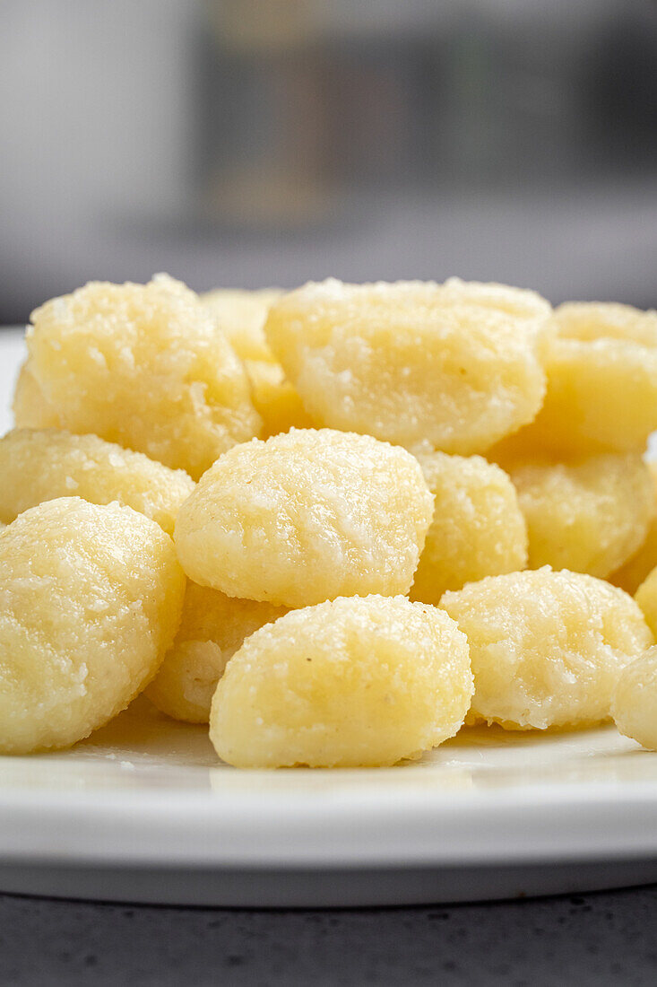 Nahaufnahme eines Tellers mit appetitlichen gelben Gnocchi, serviert auf einer Platte, die auf einem Tisch in der Küche steht