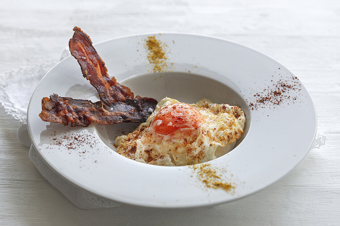 Overhead view of tasty eggs with fried bacon strips on plate