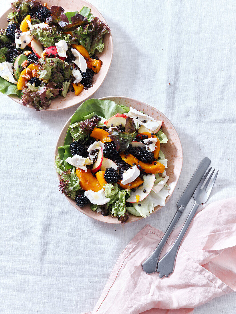 Top view with two plates of salad with roasted squash, berries and goat cheese. Vegetarian festive dinner.