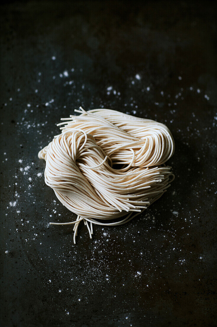 Top view of uncooked noodles for ramen preparation placed on dark background