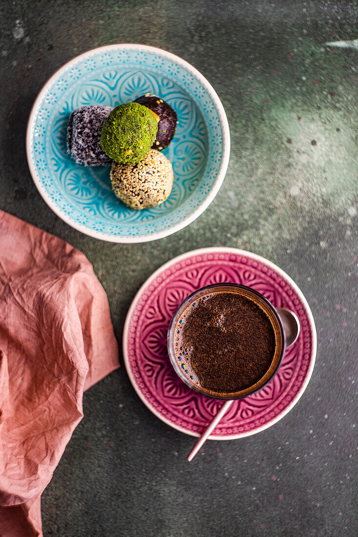 From above glass of turkish coffee and traditional pakhlava sweet balls served on green concrete table