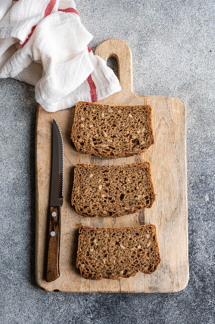 Healthy fresh baked rye bread slices on the wooden board on concrete background