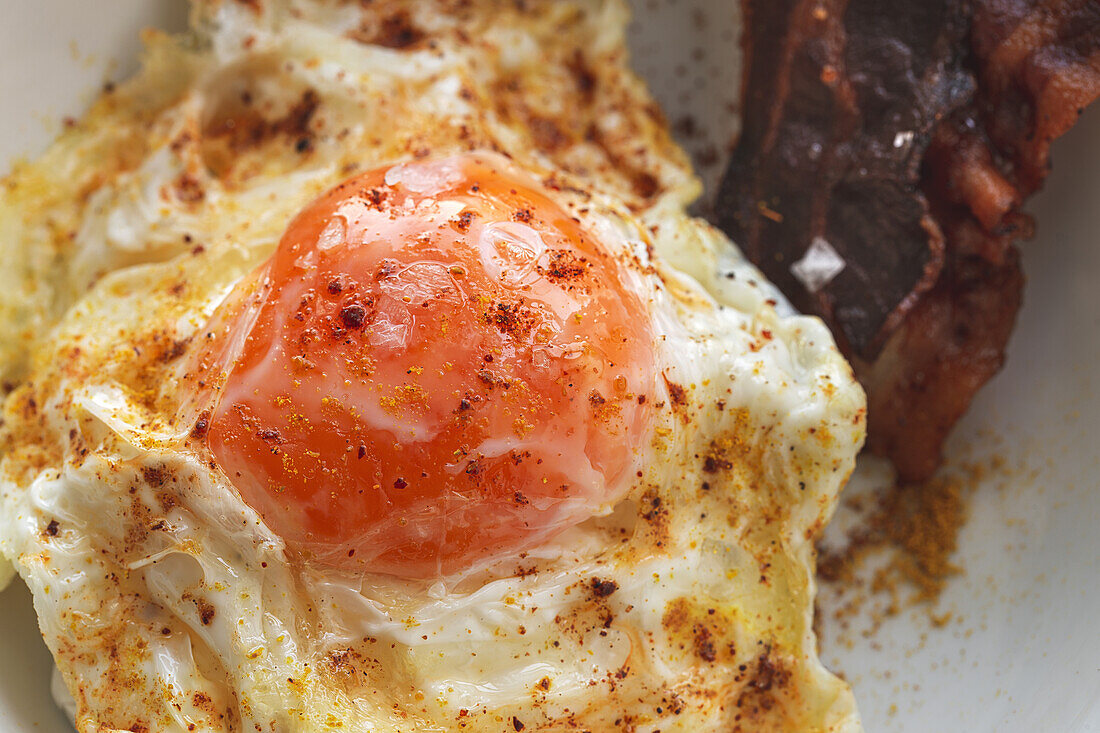 Overhead view of tasty eggs with fried bacon strips on plate