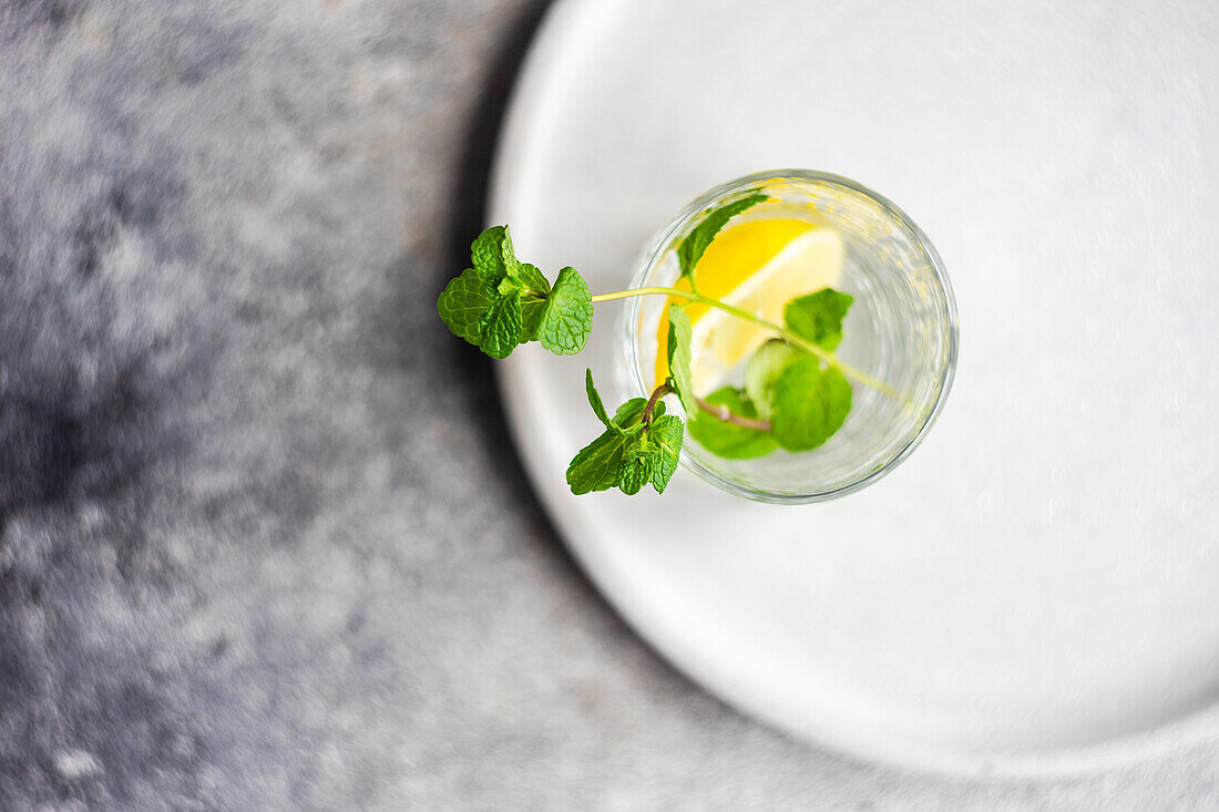 From above glass of morning pure water with lemon and fresh mint on the table