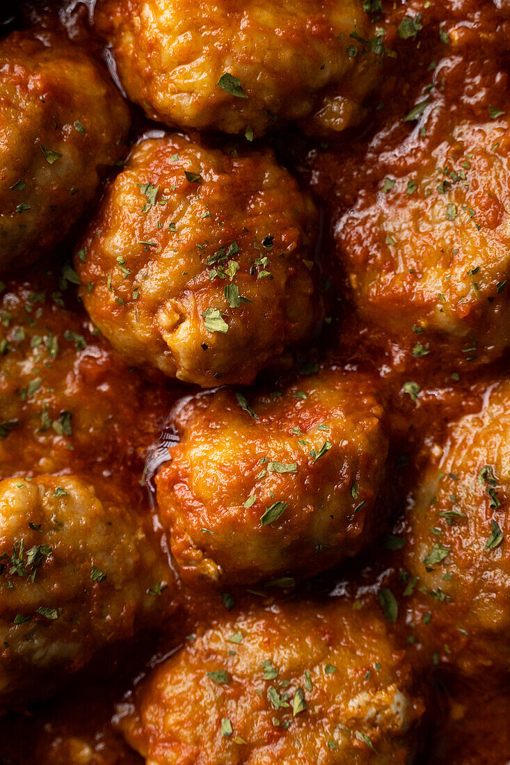 Full frame of delicious meatballs in tomato sauce with herbs