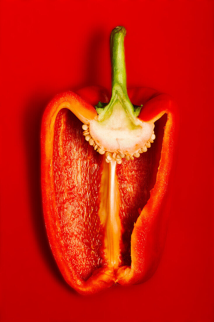 Draufsicht auf eine appetitlich geschnittene rote Paprika auf roter Fläche