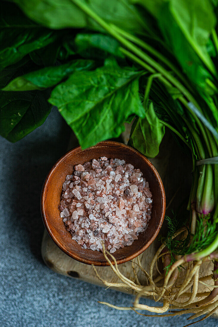 From above of fresh spinach leaves paired with aromatic spices in a wooden bowl set on a rustic backdrop ideal for creating a wholesome vegetable salad