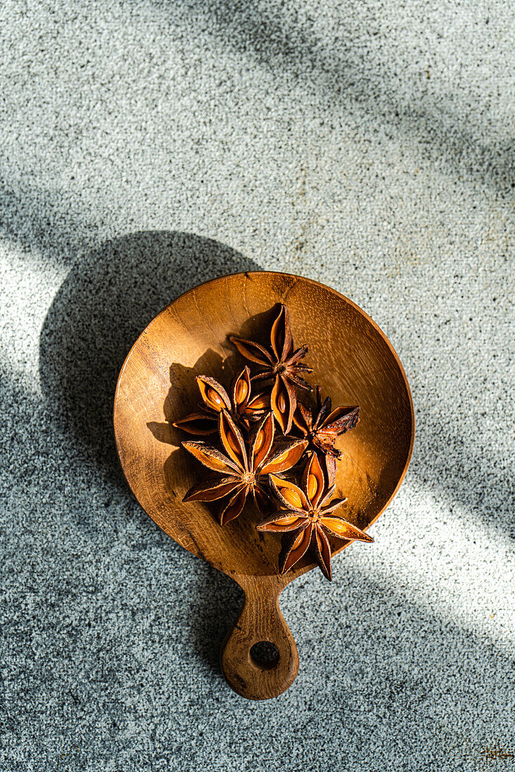 From above of wooden bowl with aromatic anise placed near table concrete background