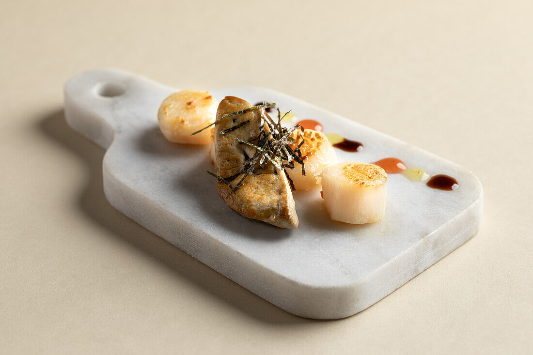From above of tasty fried scallops with foie gras served on marble cutting board with colorful sauces