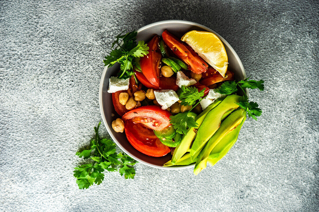 From above healthy salad with organic seasonal vegetables and avocado served on concrete table