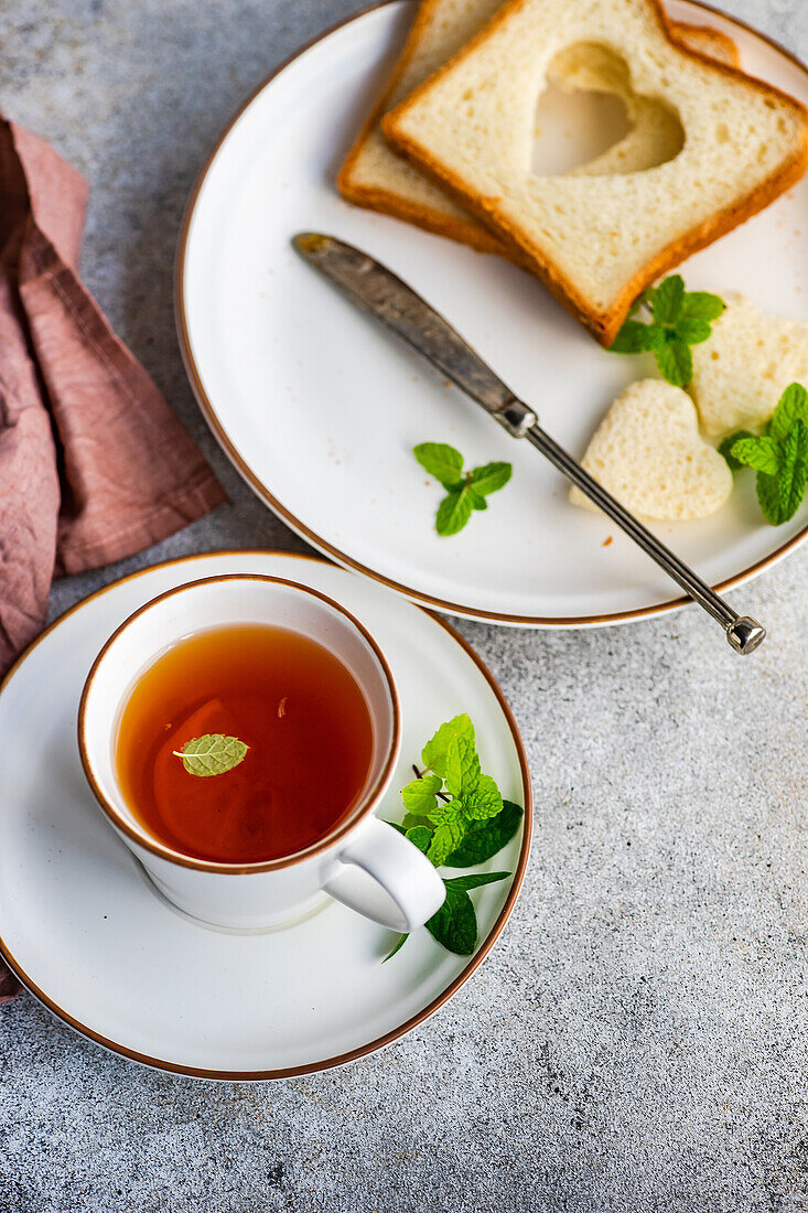 Cup of tea with lemon and toasts with heart shaped on the concrete table