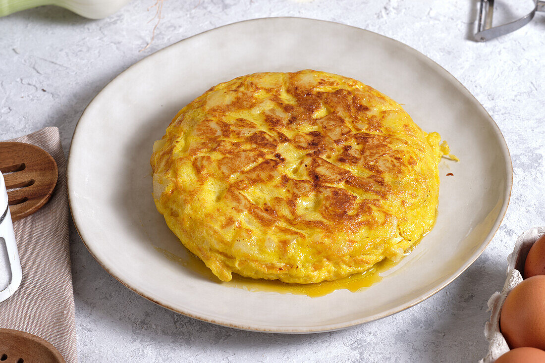 Appetitliches traditionelles spanisches Omelett auf dem Tisch mit Eiern und Zwiebeln in der heimischen Küche von oben