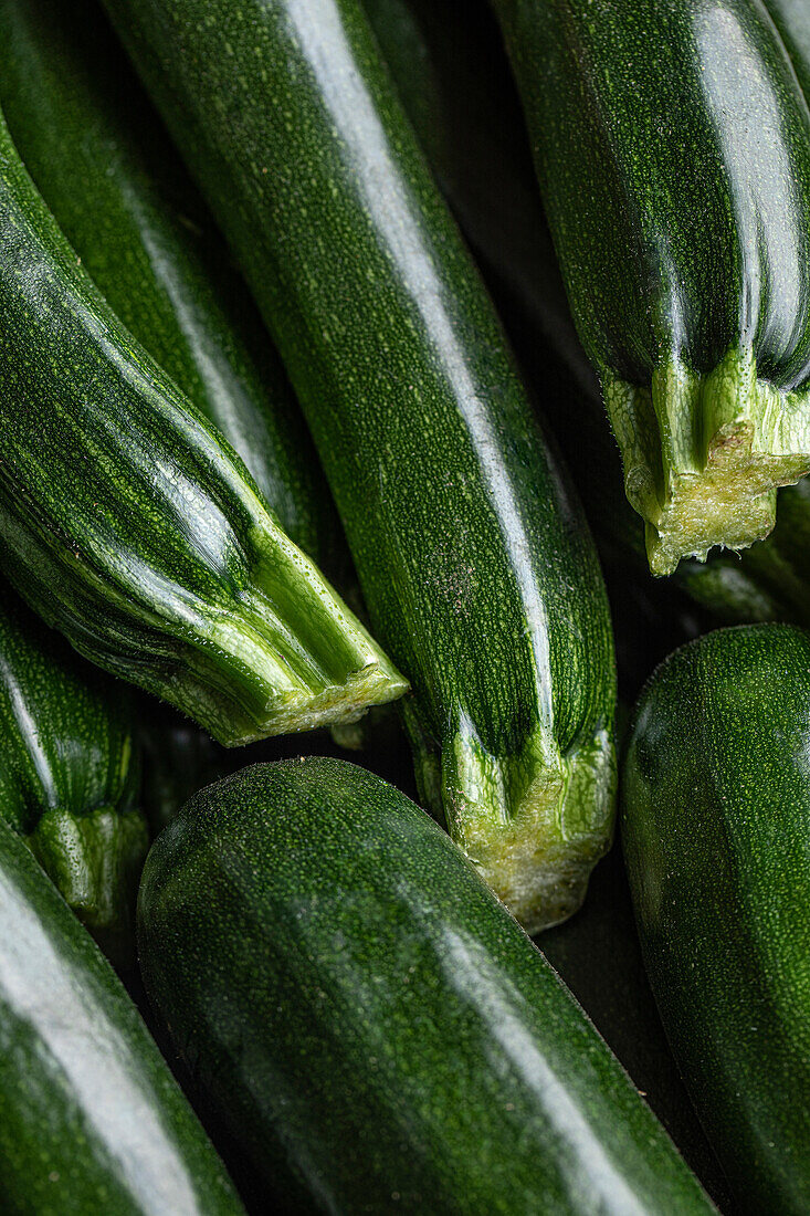Top view of stacks of green thin zucchini squashes at farmers market as background