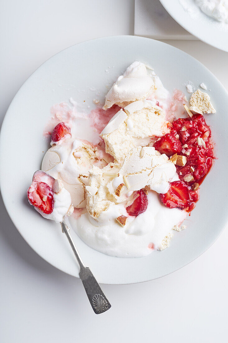 Draufsicht auf eine Nachspeise mit Beeren, Baiser und Schlagsahne. Eton's mess mit Erdbeeren, süße Leckerei mit Sommerstimmung