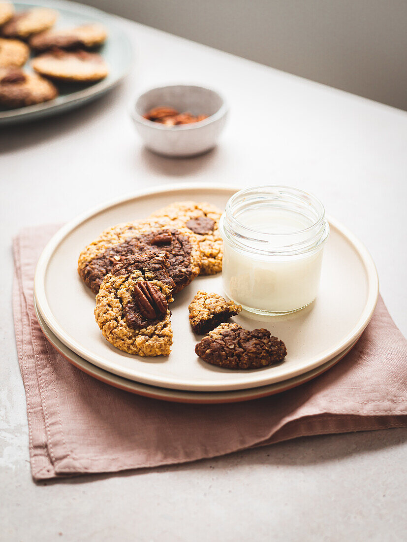 From above of sweet walnut cookies and glass of milk served on plate on table