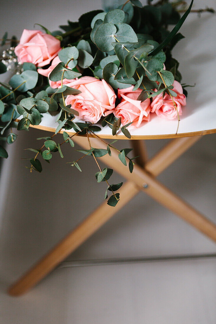 From above pink roses bouquet with green leaves lying on table