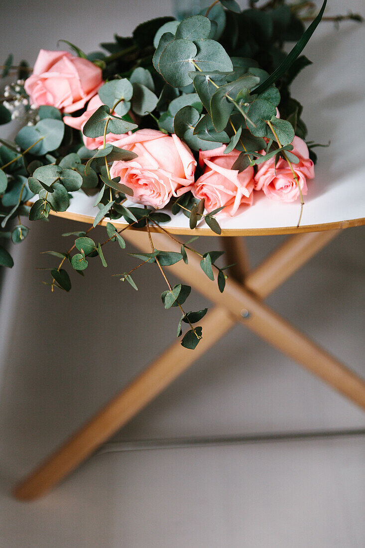 Von oben gesehen rosa Rosenstrauß mit grünen Blättern auf dem Tisch liegend