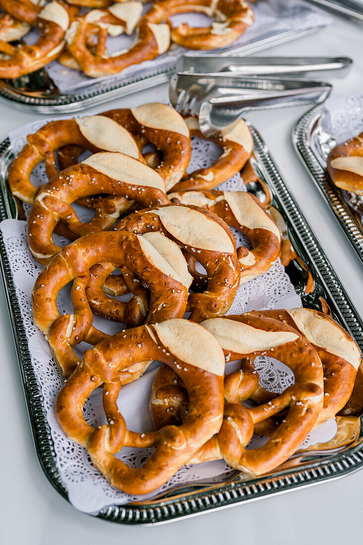 From above of delicious baked knot shaped pretzels served on metal trays and placed on table during outdoor event