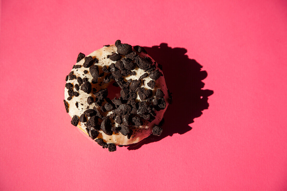 Weiße Donuts mit Oreo-Schokoladenstückchen auf rosa Hintergrund