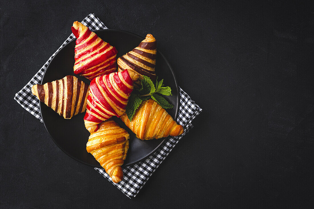 Blick von oben auf verschiedene süße Croissants, die in einem Korb auf dem Frühstückstisch serviert werden