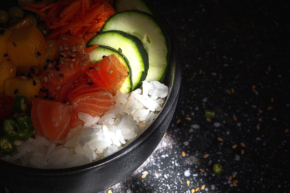 High angle of Asian poke with salmon and rice with assorted vegetables served in bowl on table in restaurant