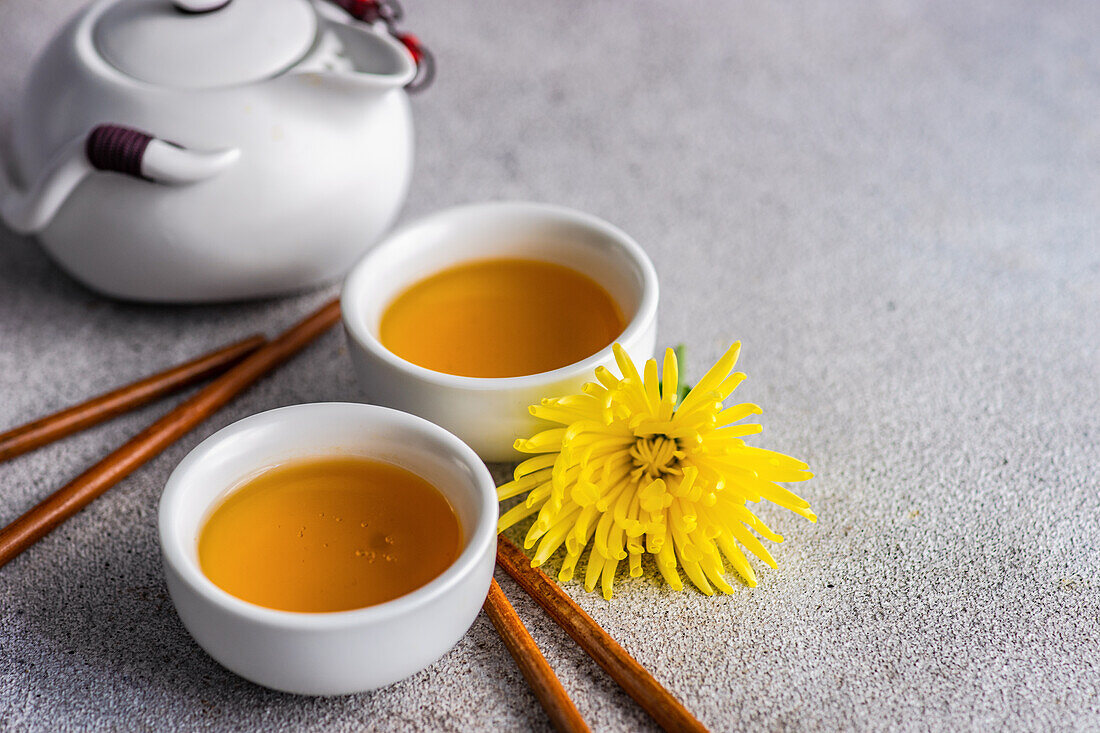 Asiatisches Grünteeset mit gelben herbstlichen Chrysanth-Blüten auf Betontisch serviert