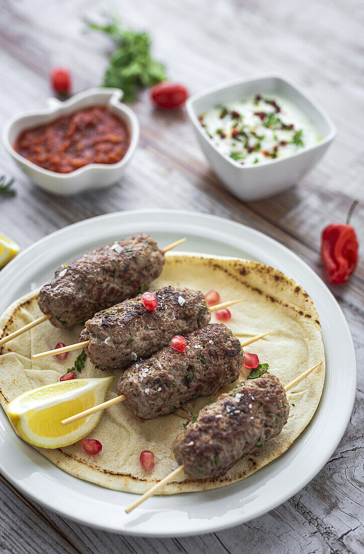 Traditional homemade kafta or kofta kebab beef and lamb with tomato sauce and yoghurt. Traditional Arabic and Turkish food. Halal food