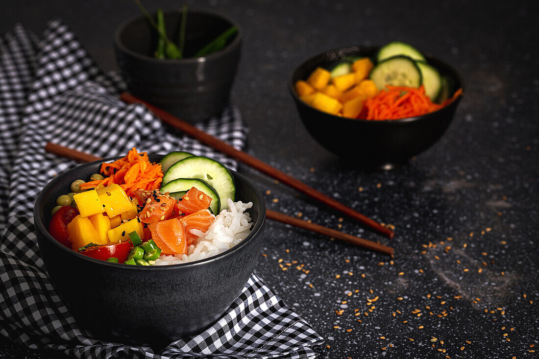 Asiatischer Poke mit Lachs und Reis mit verschiedenen Gemüsesorten, serviert in einer Schüssel auf einem Tisch mit Stäbchen in einem Restaurant