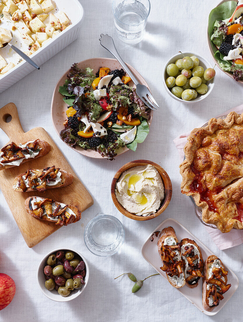 Vegetarisches Abendessen mit verschiedenen Snacks und Gerichten: Salatteller, Bruschetta, gebratenes Gemüse und ein Kuchen