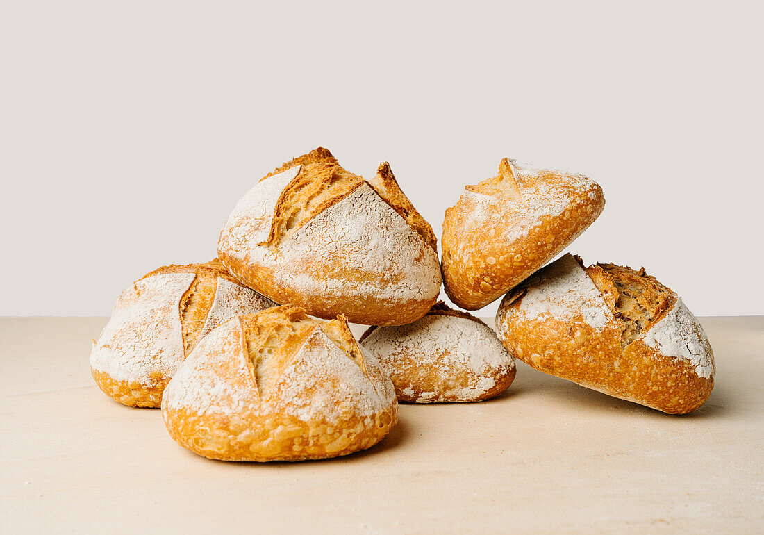 Leckeres rundes Brot mit Mehl auf goldener Oberfläche in einer Bäckerei auf weißem Hintergrund