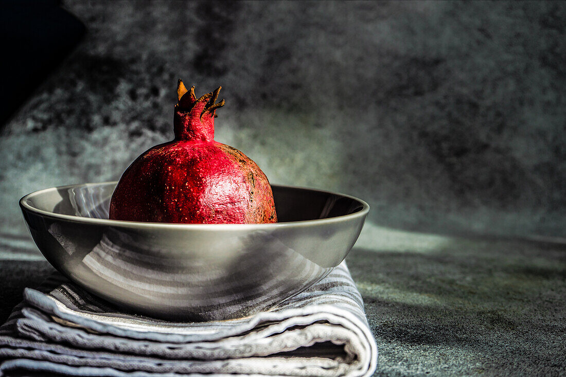 Ripe organic pomegranate fruit on the ceramic bowl and tea towel