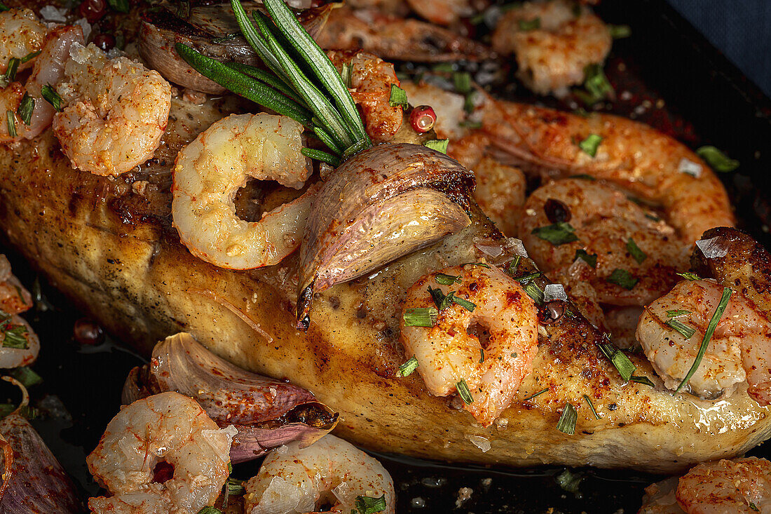 From above of black tray with appetizing baked swordfish served with prawns and confit garlic