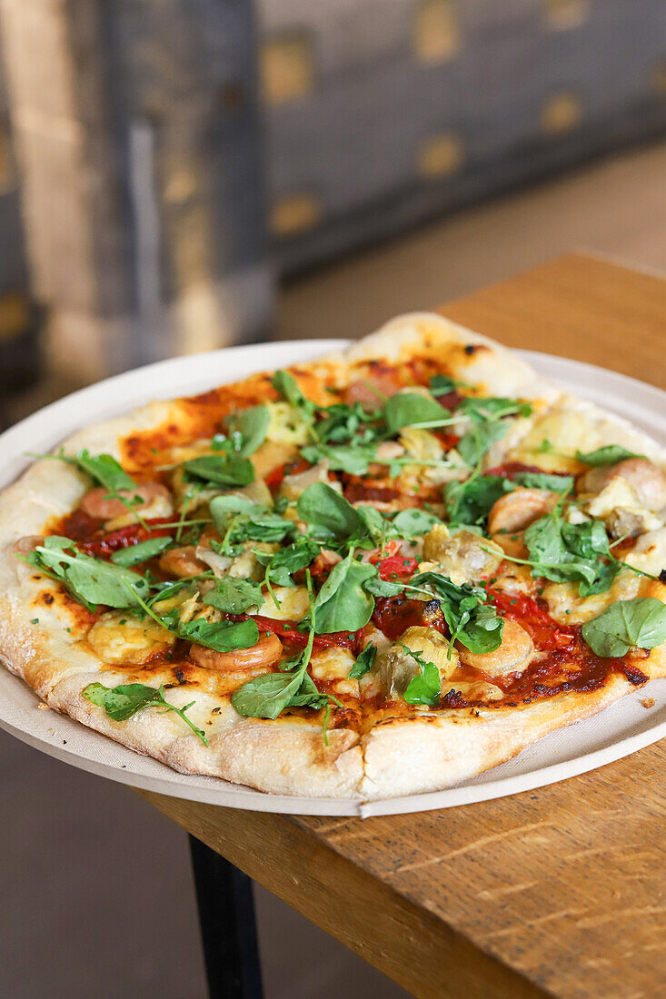 Blick von oben auf eine Pizza mit Basilikum auf einem Holztisch