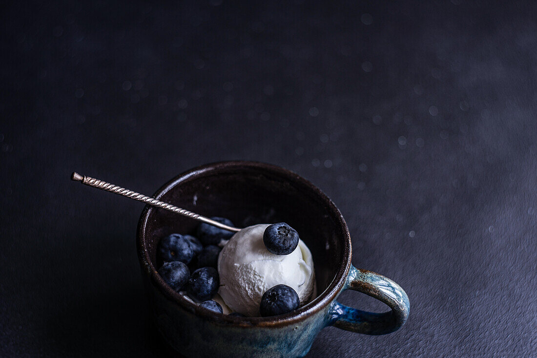 Von oben Schüssel voll mit köstlichen reifen Blaubeeren auf schwarzem Hintergrund platziert