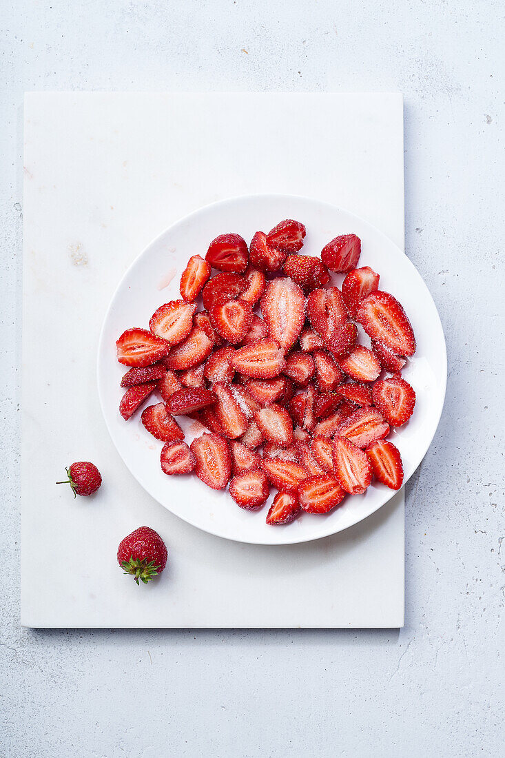 In Scheiben geschnittene Erdbeeren mit Zucker überzogen auf einem Teller. Kochen von Dessert oder Marmelade