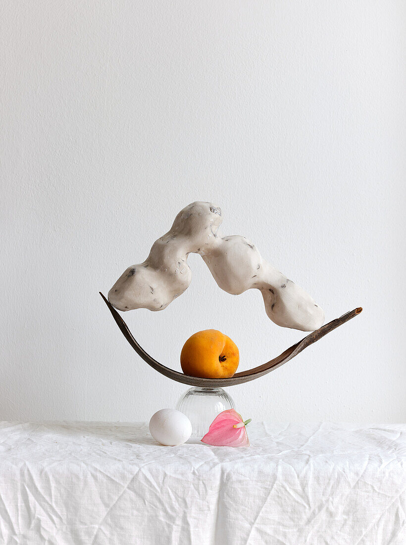 Arrangement with handmade sculpture and a peach