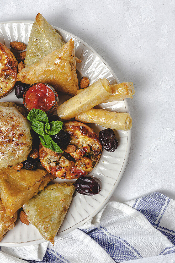 Blick von oben auf verschiedene leckere arabische Speisen mit Salsa und frischen Minzblättern in der Nähe von Mandeln während des Ramadan-Festes