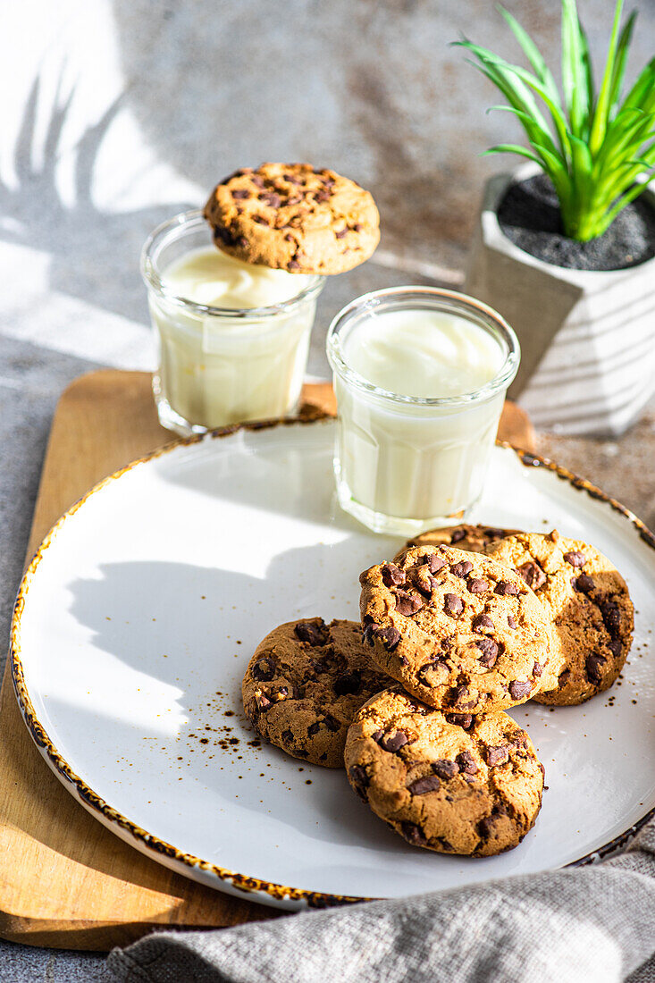 Healthy oat cookies with chocolate and glass of yogurt on the concrete or stone table