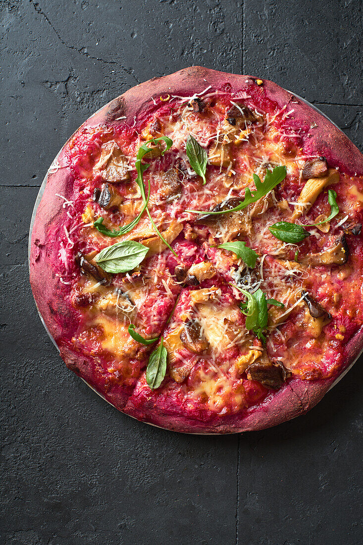 Lila gefärbte rustikale Pizza mit Roter Bete und vegetarischem Belag. Ansicht von oben gesundes Essen Rezept