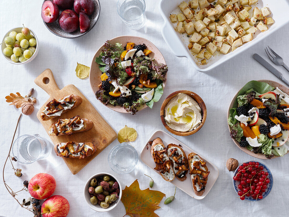 Vegetarian dinner with various snacks and dishes: salad plates, bruschetta, roasted vegetables and a pie