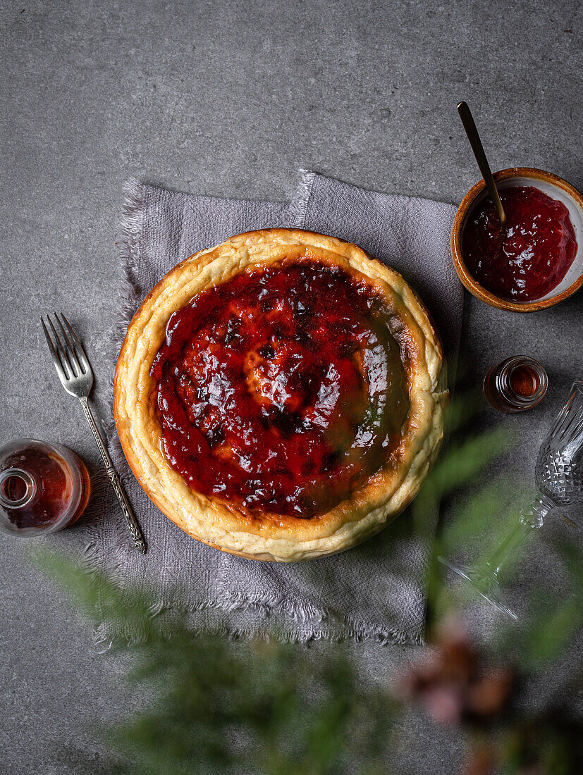 From above of yummy homemade sweet cheesecake placed against jar with sauces and bowl of jam on gray table