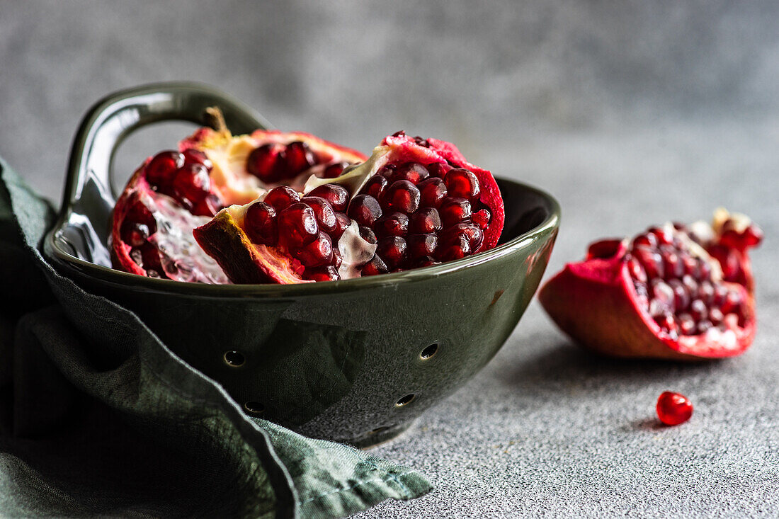 Organic ripe pomegranate fruit in ceramic bowl on stone background
