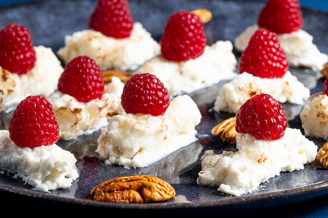 Appetizing delicious creamy dessert with fresh ripe raspberries with pecan nuts placed on plate in cafe