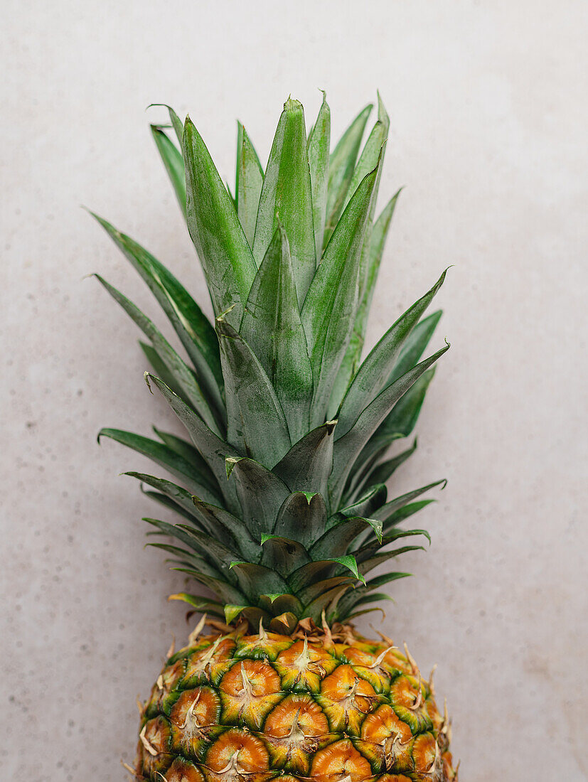 From above of ripe whole sweet pineapple placed on stone table in kitchen