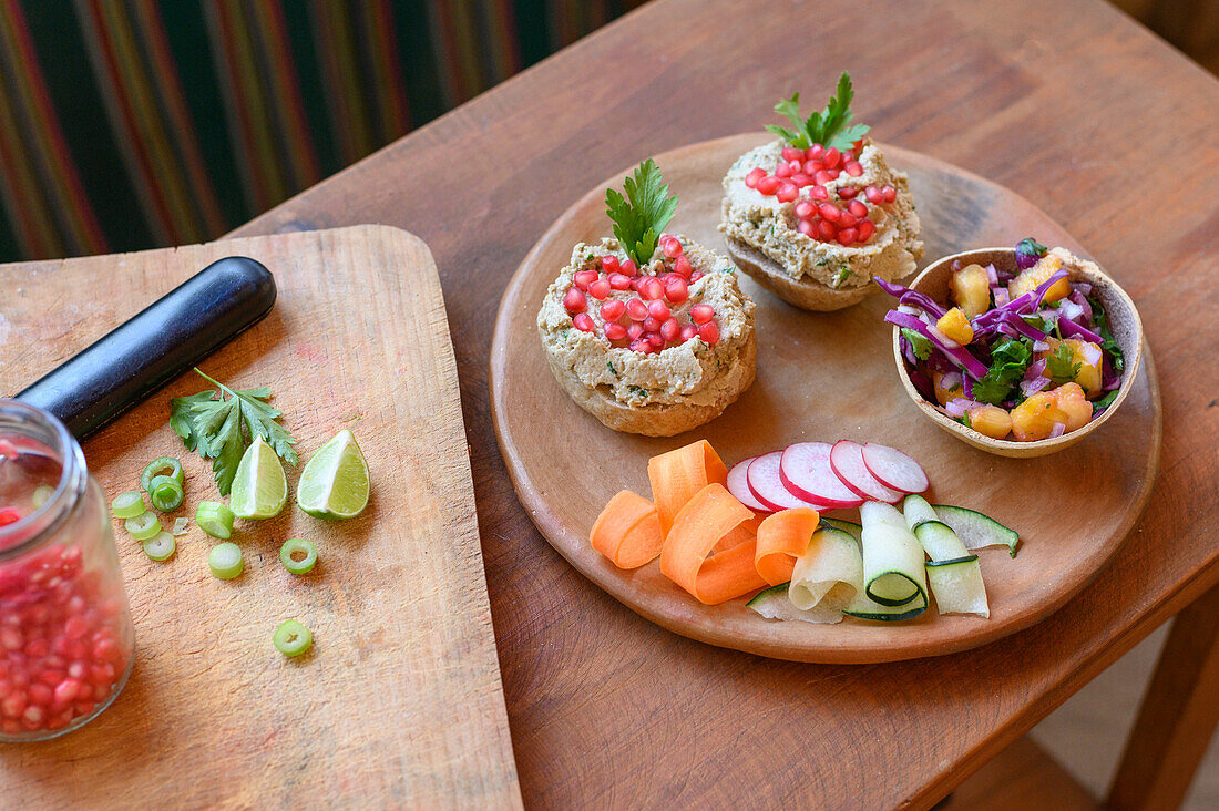Von oben Schüssel mit frischem Salat auf Holzteller mit geschnittenem Gemüse und Sandwiches mit Pilzpastete für vegetarisches Mittagessen vorbereitet