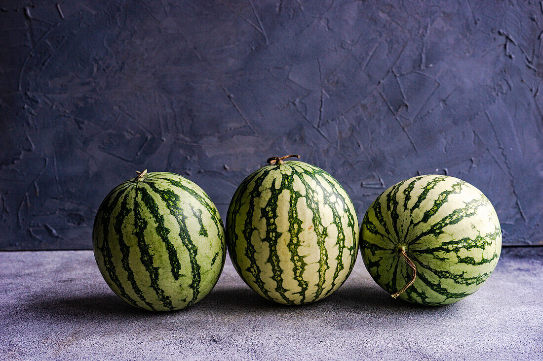 Still life composition of whole ripe striped green watermelon on concrete background